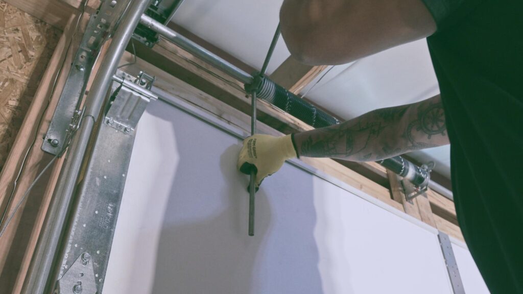 Technician adjusting garage door torsion spring